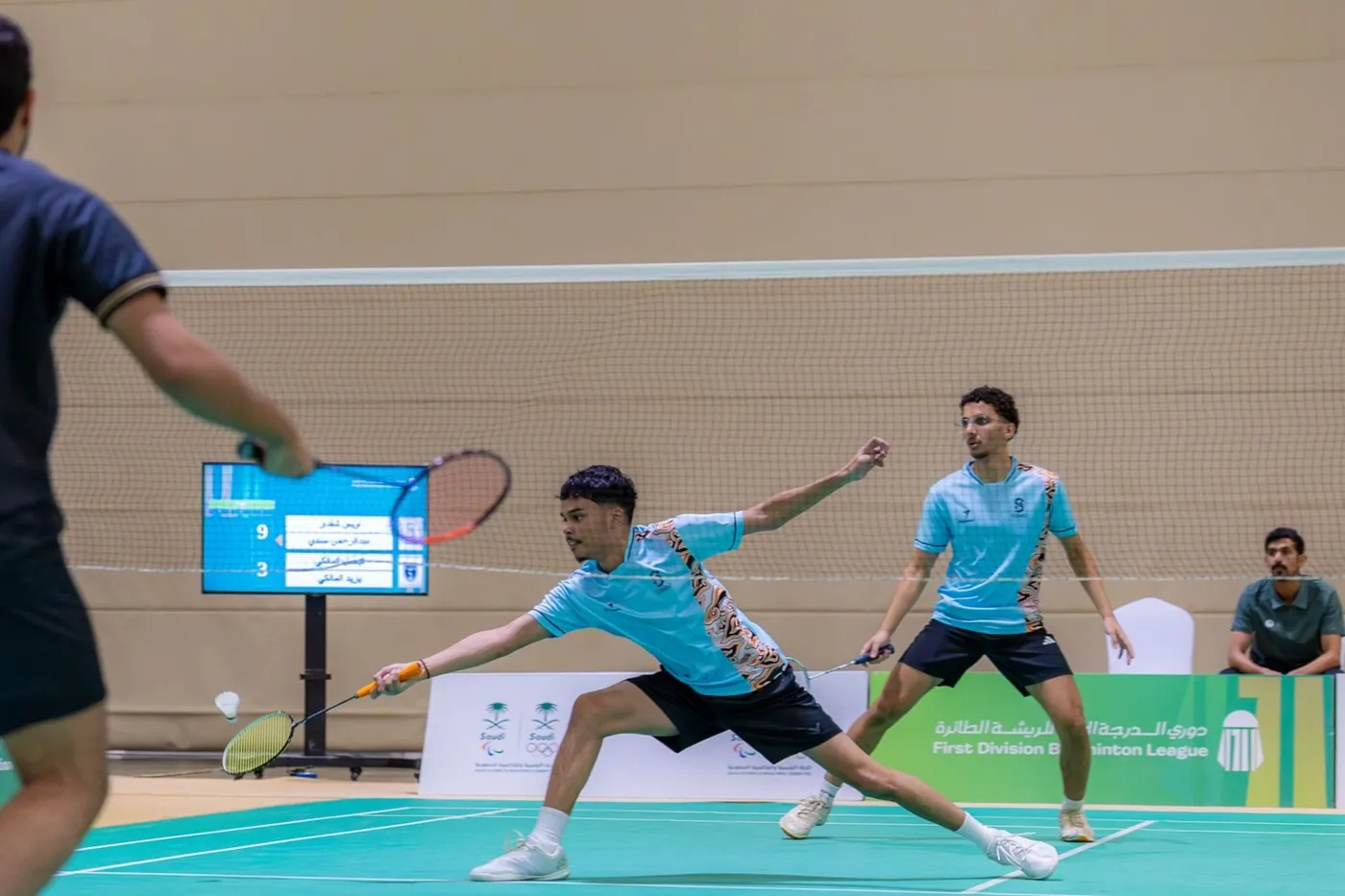 Doppelspieler strecken sich nach dem Federball auf einem Court der Saudi Badminton Federation